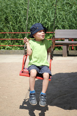 kleiner Junge im Kettenkarussel jauchzt vor Freude