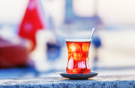 Turkey, Istanbul. Istanbul traveling welcome concept. Traditional Turkish glass of tea on parapet at Maiden tower background. Sunset time scene.