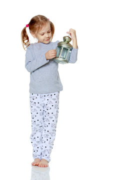 A Little Girl Is Holding A Lamp.