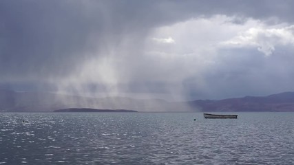 Boat floating in Ohrid Lake against rainy clouds, Macedonia