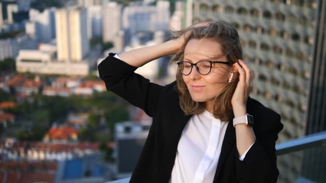 Business Woman Listening Music Using Bluetooth Wireless Earphones In City