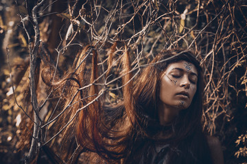 Beautiful young woman model with very long hair on branches. witch craftconcept