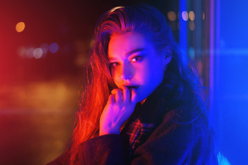 Sexy young woman posing over night city dramatic neon background