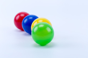 Lined up four colored plastic balls of game room swimming pool for fun and jumping, green, yellow, blue and red.