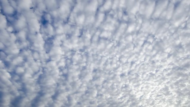 Time lapse shot of white altocumulus clouds passing overhead.