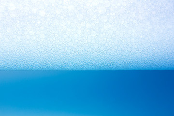 Soap bubbles float on blue water, texture background