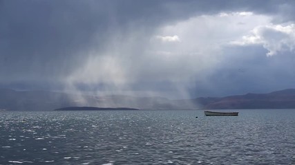 Boat floating in Ohrid Lake against rainy clouds, Macedonia