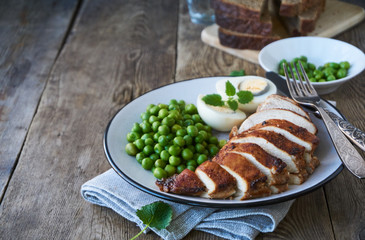Baked chicken breast, egg and green peas on a plate