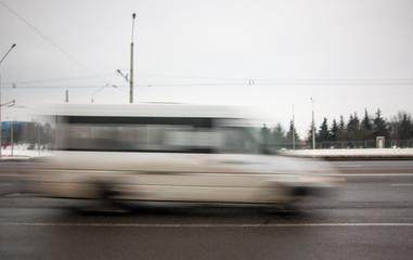 Movement of a blurred white minibus along the highway during the day