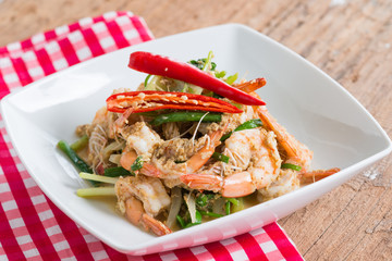Stir-Fried Shrimp with Curry Powder in white plate on brown wood background