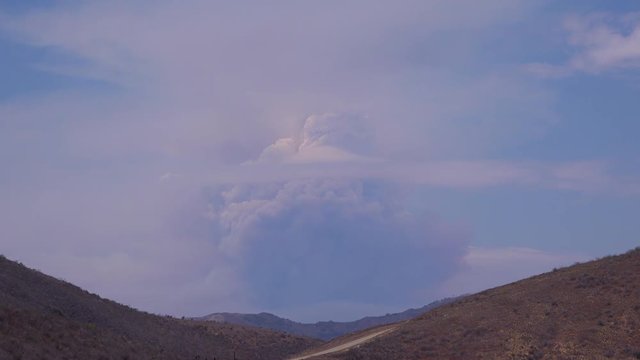 A timelapse shot of smoke rising in a huge mushroom cloud as a wildfire rages.