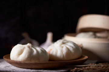 Fototapeta na wymiar Chinese breakfast: Steamed buns (Baozi) on wooden plate, with ba