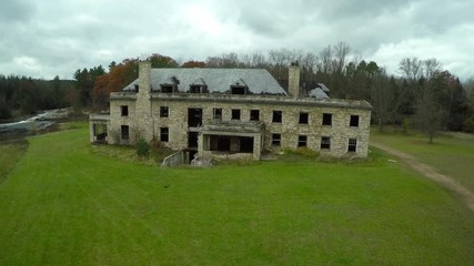 An aerial over a spooky abandoned mansion in the countryside.