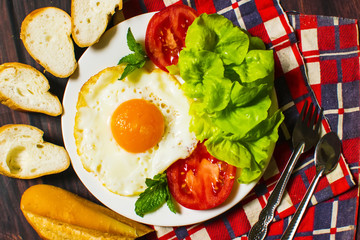 Breakfast with bread, fried eggs, milk and vegetables and fried tomato pieces on wood background