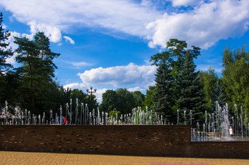 Fototapeta na wymiar Fountain in city park on hot summer day