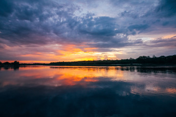 Beautiful sunset over a river with heavy clouds