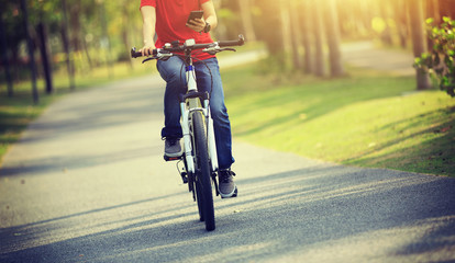 Naklejka na ściany i meble cyclist use cellphone while riding bike in tropical park