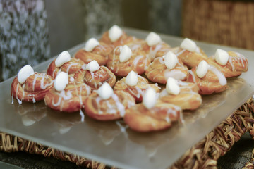 Homemade profiteroles served with blueberries on a white plate, Baked round profiteroles with white cream and cupcakes with on board, selective focus and shallow depth of field