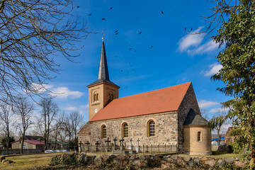 Fototapeta na wymiar Vogelschwarm über der denkmalgeschützten Dorfkirche in Jühnsdorf