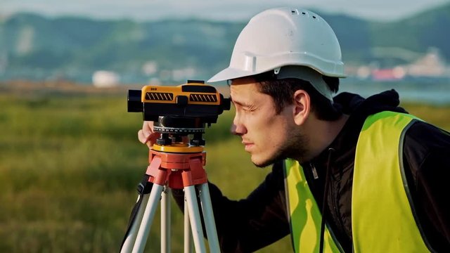 Surveyor engineer is measuring level on construction site. Geodesist ensure precise measurements before undertaking large construction projects. Concept of landscape design