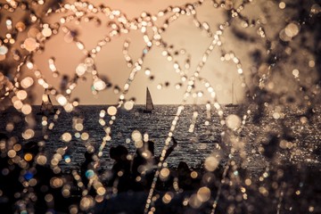 sail boat silhouette in the sea during the sunset with peoples's silhouettes and waterdrops of a...