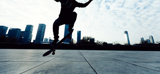 skateboarder legs jumping with skateboard at city
