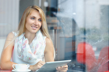 Young businesswoman looking at touch pad screen while standing in cafe