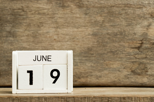 White block calendar present date 19 and month June on wood background