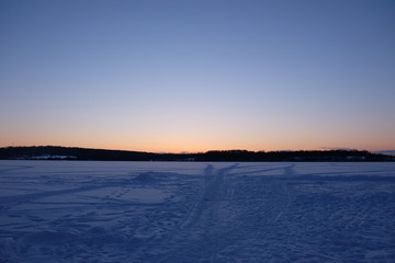 Winter landscape with lake and sunset fiery sky