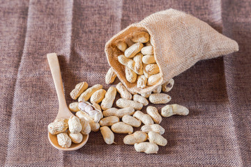Roasted nuts peanut baked salt with burlap sack on wooden background