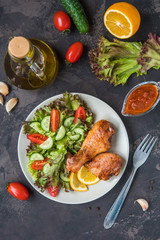 Fried chicken legs and fresh salad on a dark background