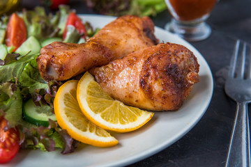 Fried chicken legs and fresh salad on a dark background