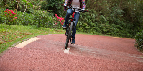 Naklejka premium woman cyclist riding bike on forest trail