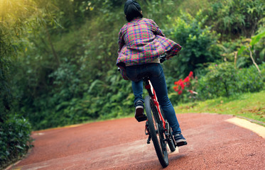 woman cyclist riding bike on forest trail