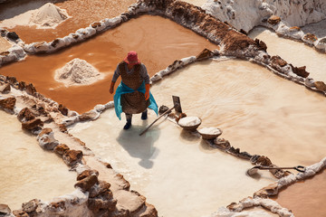 Woman working at the salt terraces in Maras - obrazy, fototapety, plakaty