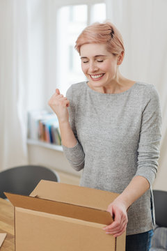 Excited young woman opening a brown cardboard box