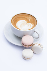 Coffee latte in a white mug and dessert macaroons on a white background.