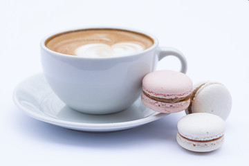 Coffee latte in a white mug and dessert macaroons on a white background.