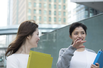 2人のOLがオフィス街で会話しながら歩いている