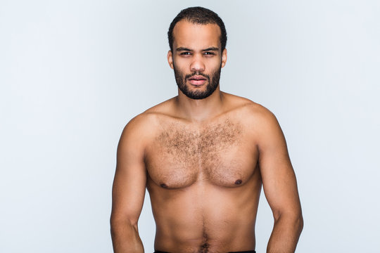 Macho man. Portrait of handsome shirtless young black man looking at camera while standing against white background