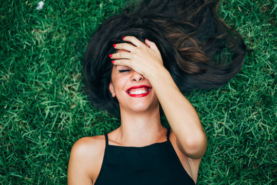 Cheerful brunette woman lying in grass