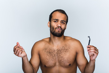 Don’t like this razor. Portrait of handsome shirtless young black man looking at camera and...