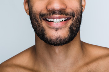 Obraz premium Cheerful smile. Close up part of handsome young black man smiling while standing against white background