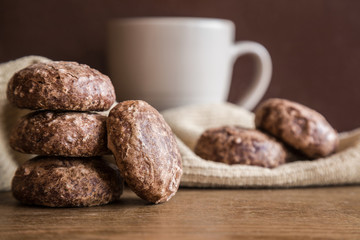 Glazed, chocolate russian gingerbreads or small spice cakes with mug of beverage on the dark, wooden vintage table. Enjoying coffee and sweets. Drink and snack concept.