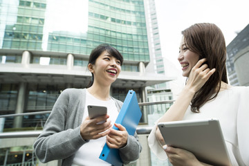 女性たちがオフィスビルの下で会話している