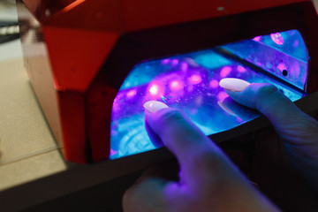 UV lamp for nails. The client dries his hand with gel varnish applied in a special lamp. Manicure concept