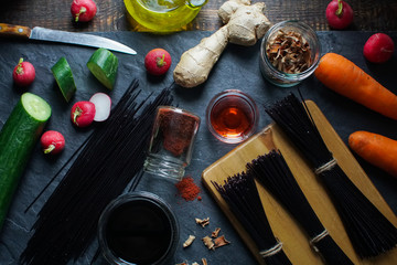 Black rice vermicelli, vinegar and vegetables on a black slate view from above. Asian cuisine
