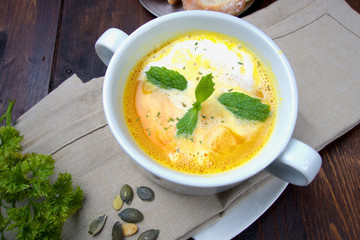 Hot pumpkin soup with green herb and homemade healthy bread