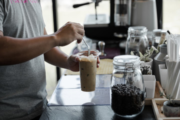 male barista poured coffee into a glass in the workplace at cafe. Iced coffee
