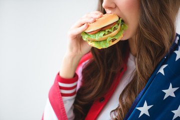 cropped image of sexy girl in usa flag eating burger isolated on white